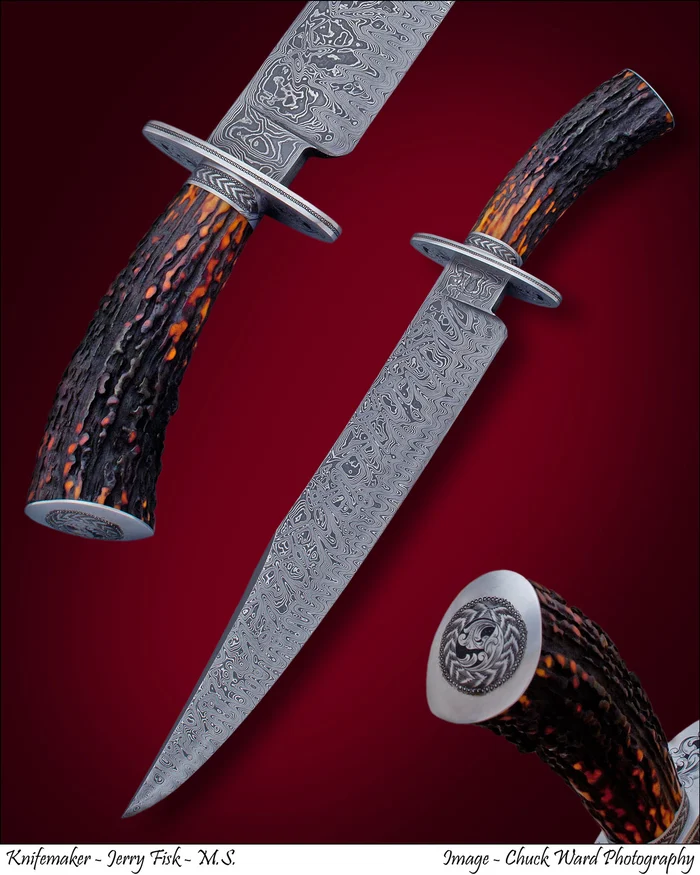 A large Damascus bowie with a stag handle and a coin-like engraved medallion, on a red ground.