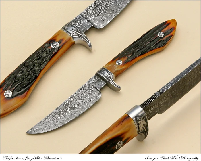 Three Damascus knives with ivory handles on a warm ochre ground.